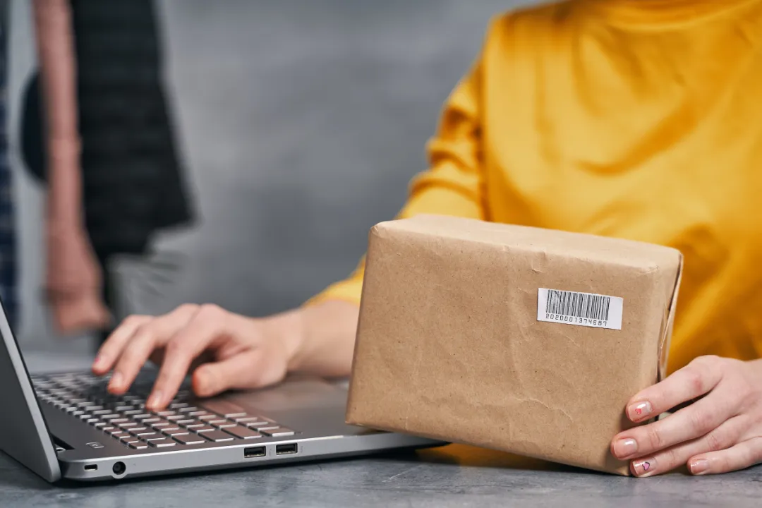 152876503_m Woman sending parcel using her laptop. Working from home